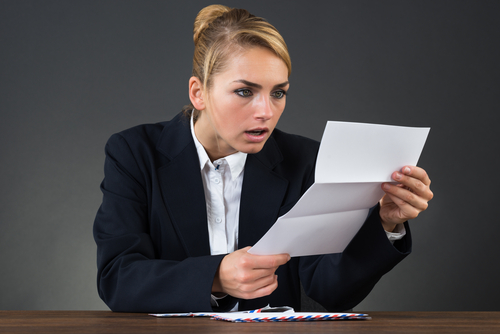Business woman looking shocked at the letter she is reading