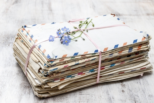 Stack of envelopes bound together with a flower on top